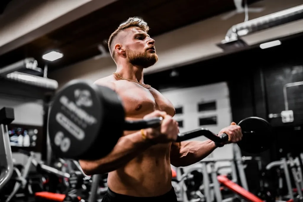 Muscular man doing barbell bicep curls during a strength workout at the gym