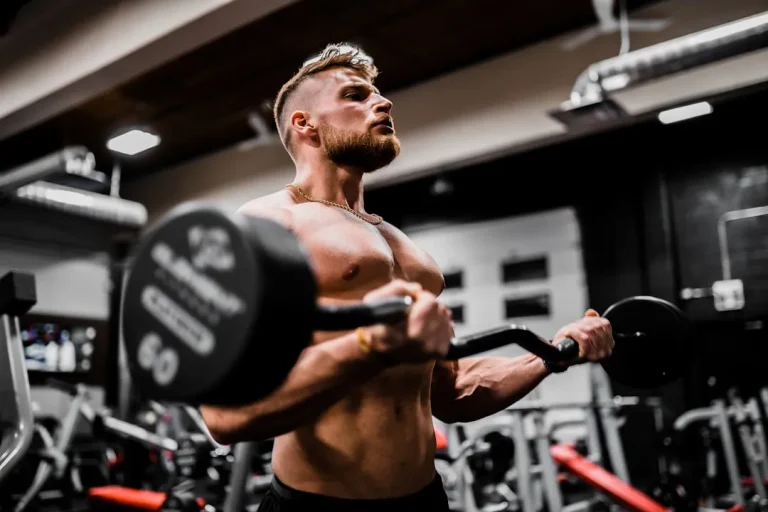 Muscular man doing barbell bicep curls during a strength workout at the gym